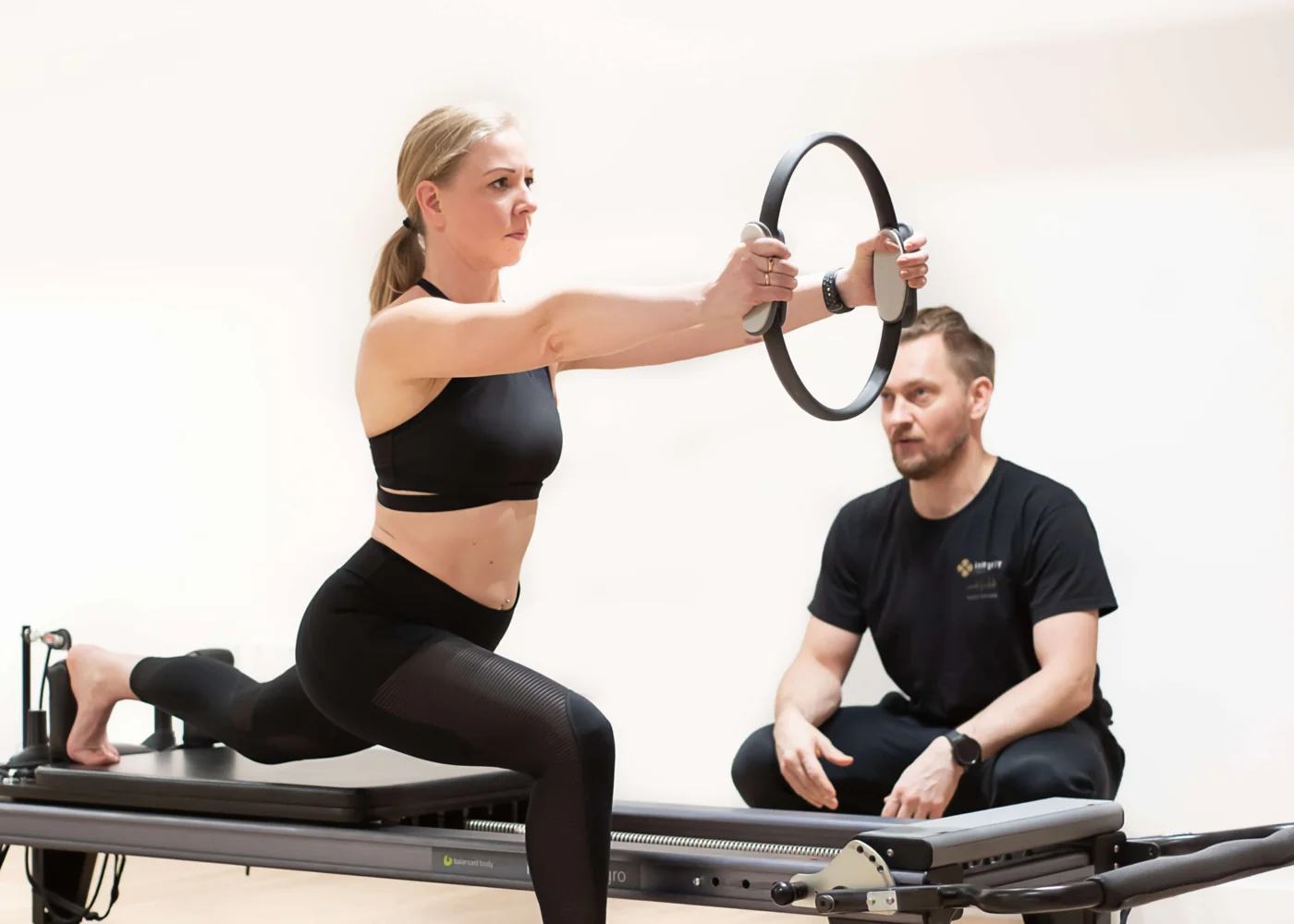 Irek guiding a client through a Pilates ring exercise on the Reformer